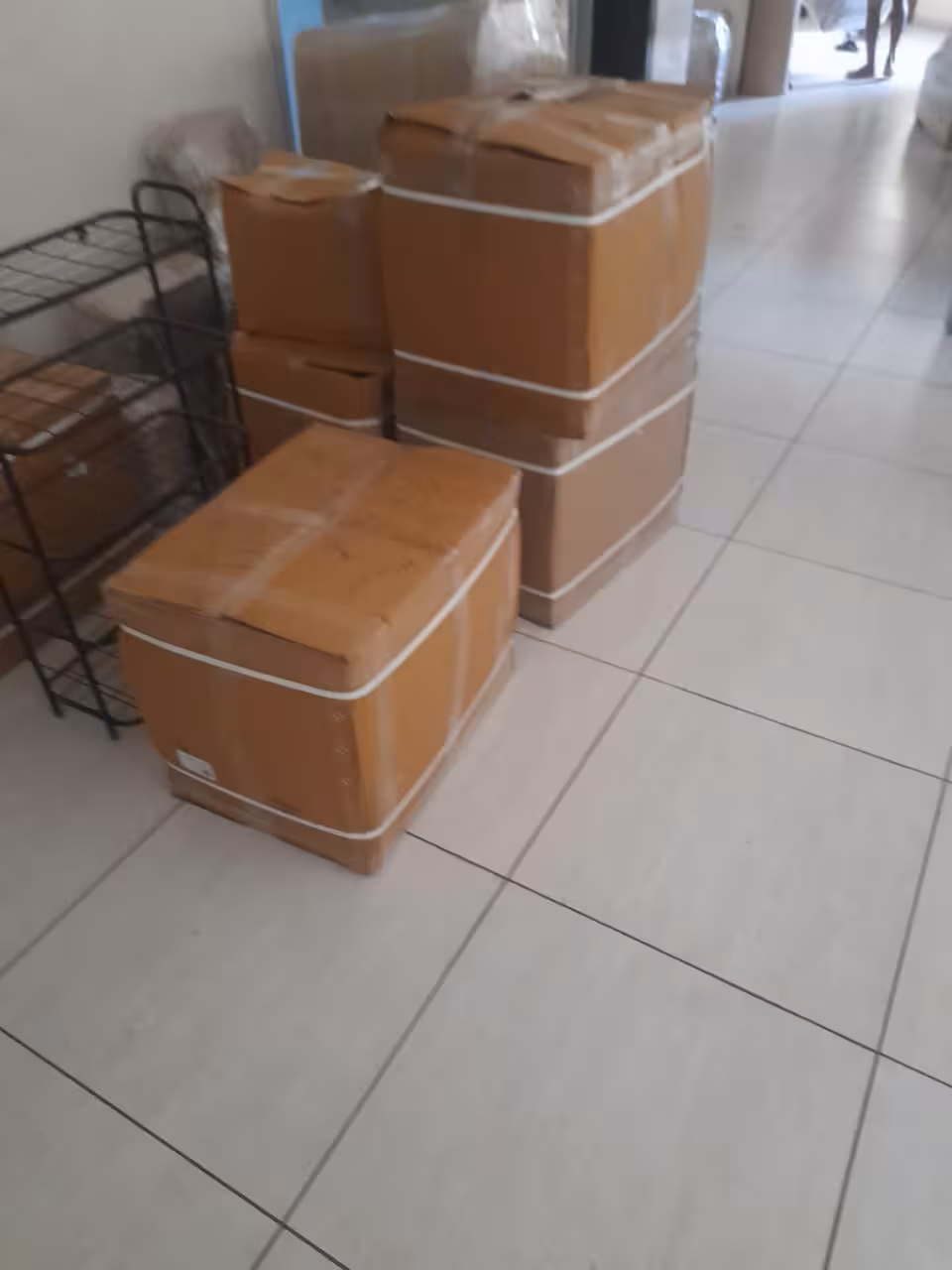 Several packed cardboard boxes stacked on a tiled floor