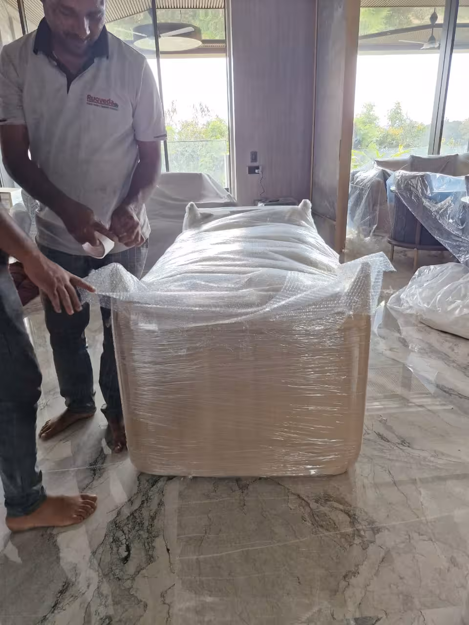 Professional movers wrapping a sofa with plastic film