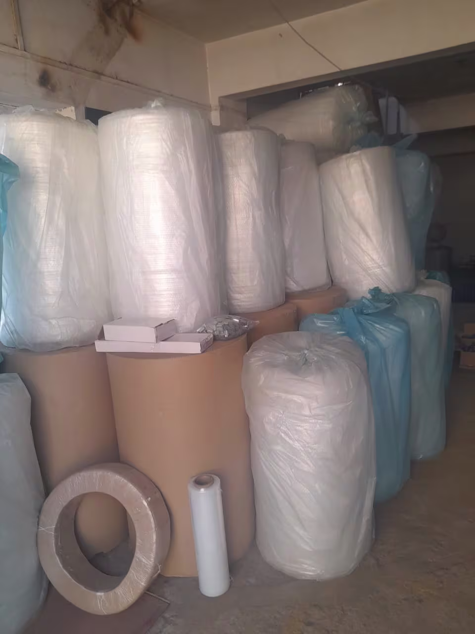 Various packing materials, including large rolls of bubble wrap and cardboard, stacked in a storage area.